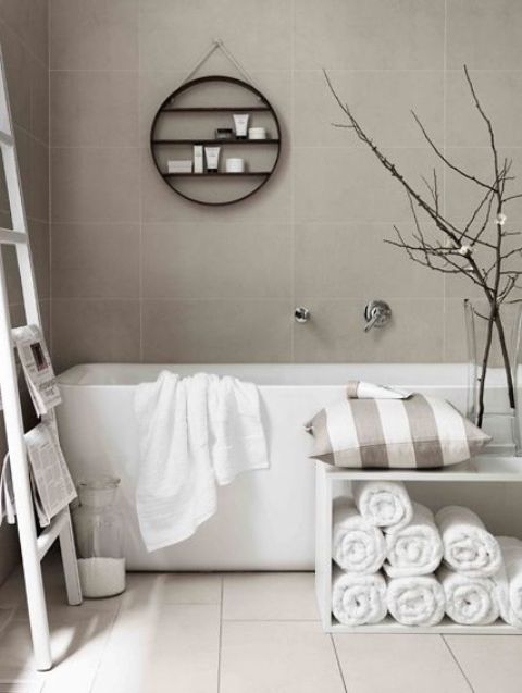 a contemporary greige bathroom with a white floor, a square tub, a white storage unit and a ladder, a hanging shelf and a vase with branches