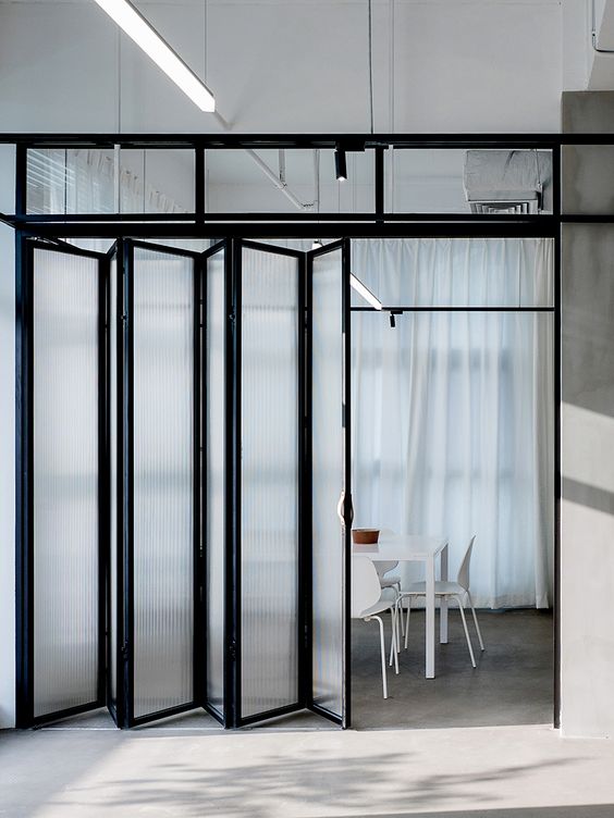 a contemporary industrial space with a black frame and frosted glass door that matches the decor and stylishly divides the spaces