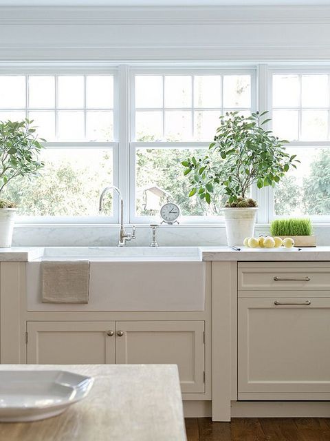 a delicate greige kitchen with shaker cabinets, white stone countertops, vintage fixtures and a window row as a backsplash is subtle and pretty