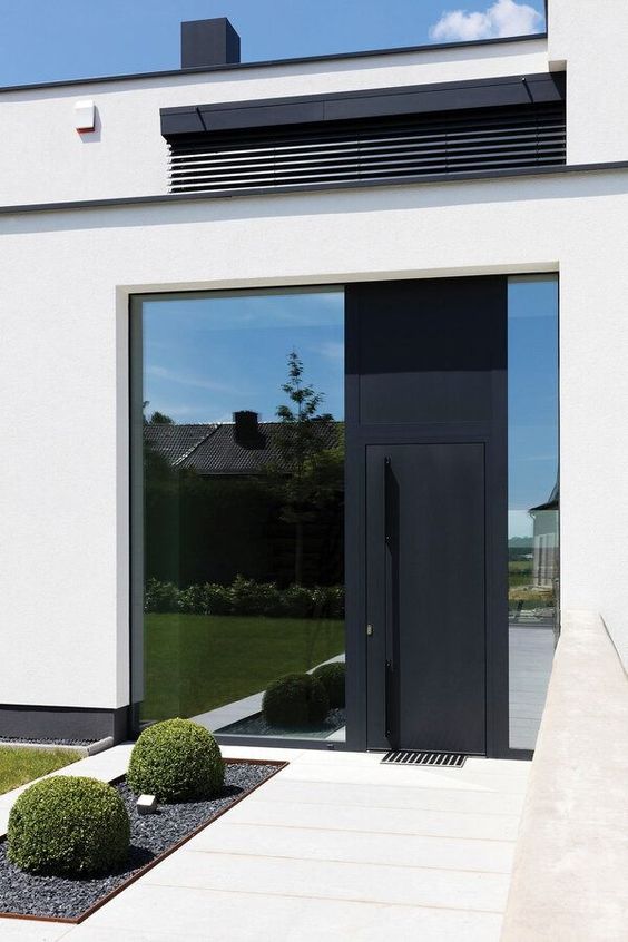 a large and a narrow window plus a black metal front door with an oversized handle on it is a cool solution for a modern house