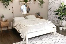 a lovely bedroom with a greige accent wall and a whitewashed brick one, a white bed with creamy bedding, stained nightstands and potted greenery