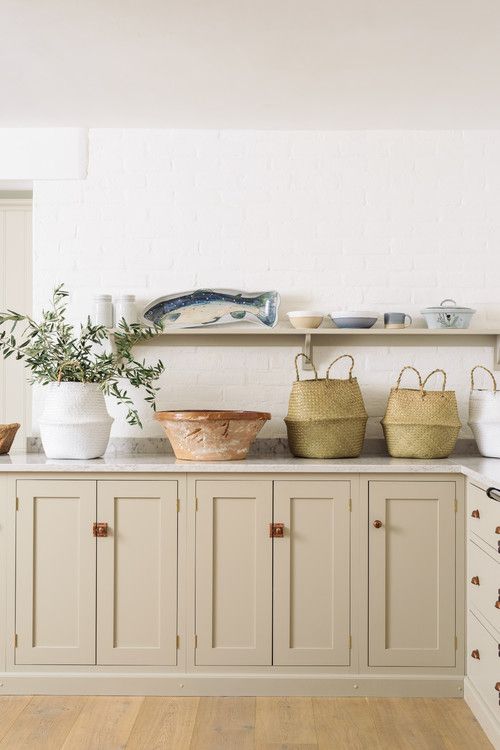 a lovely farmhouse greige kitchen with shaker only lower cabinets, white stone countertops and a long open shelf instead of upper cabinetry