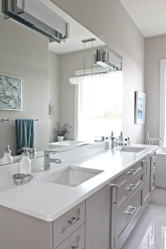 a modern farmhouse greige bathroom with a matching vanity with a white stone countertop, white appliances and neutral fixtures plus wall lamps