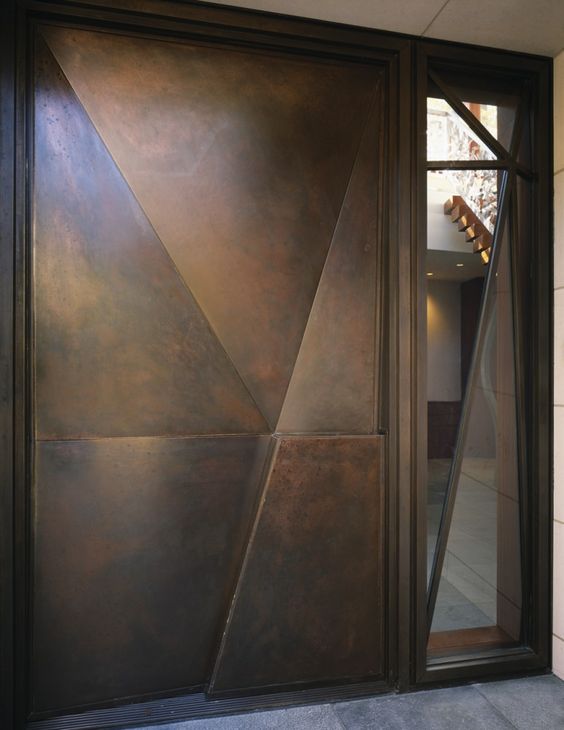 a modern geometric dark metal door with a 3D part and with a window by its side is a cool idea for a modern home