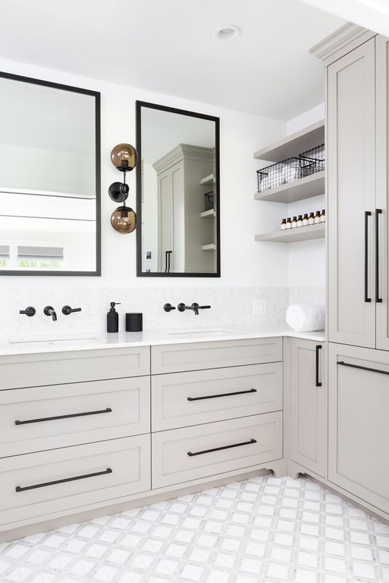 a neutral bathroom with greige cabinetry, white stone countertops and black fixtures, mirrors in black frames is a cool and stylish space