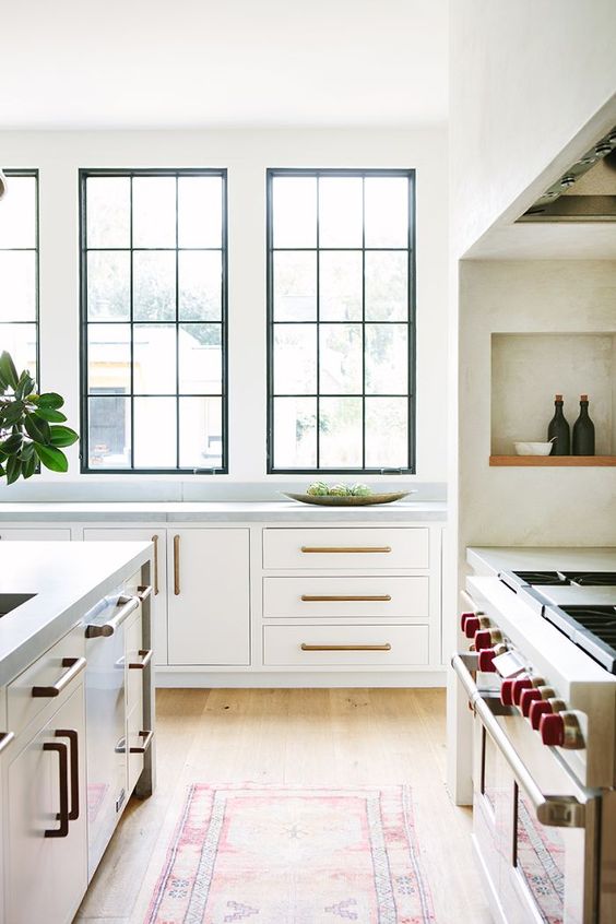 a neutral kitchen with grey stone countertops and black painted double height French windows is a lovely and cool space