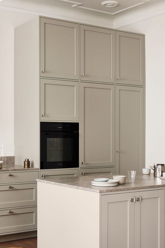 a pretty Scandinavian greige kitchen with shaker cabinets, taupe stone countertops, built-in appliances and elegant fixtures