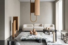 a refined greige living room with curved seating furniture, a white stone coffee table, a wooden pendant lamp and a matching decoration is chic
