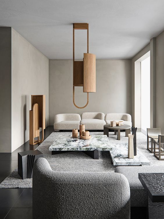 a refined greige living room with curved seating furniture, a white stone coffee table, a wooden pendant lamp and a matching decoration is chic