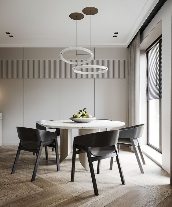 a sleek and refined minimalist dining room with greige walls, a round table, black chairs, round chandeliers and natural light