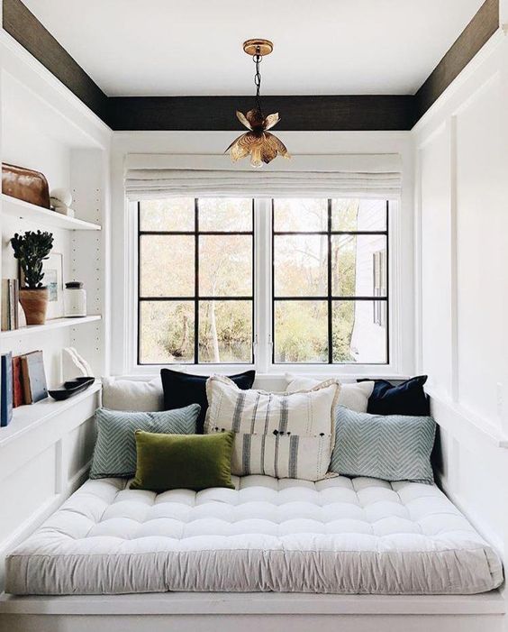 a small contemporary reading nook by the window, with some shelves built-in and colorful pillows