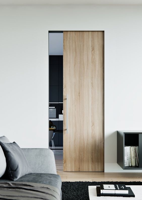 a small light-stained pocket door with sleek and long handle is a stylish way to separate the spaces ina  contemporary home