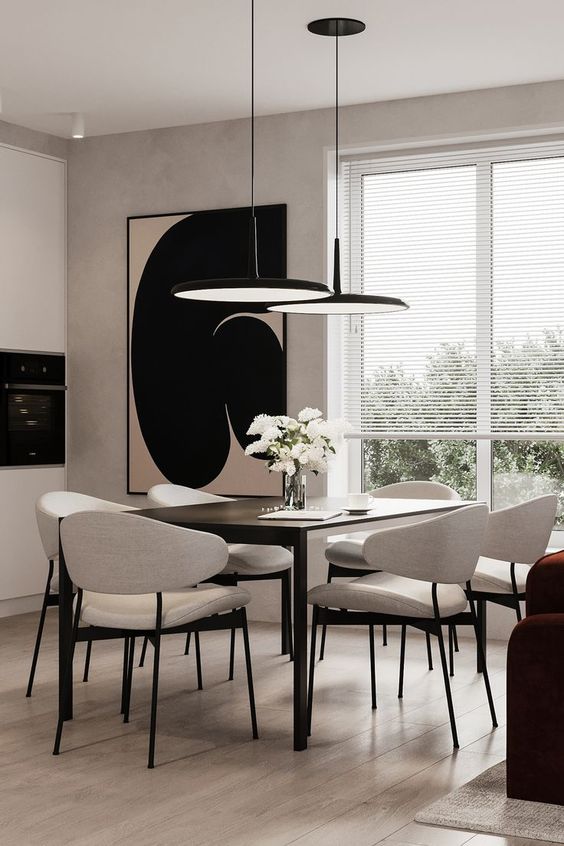 a stylish greige dining room with a black table, neutral chairs, black pendant lamps, a statement artwork and a burgundy sofa is wow