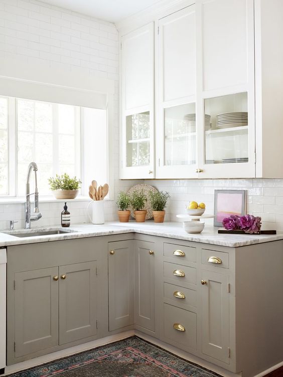 a two-tone kitchen with white upper and greige lower cabinets, white stone countertops, a skinyn tile backsplash is a lovely and trendy space