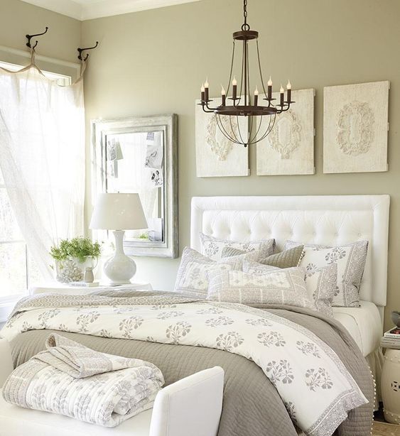 a vintage greige bedroom with a white upholstered bed, a white upholstered bench, a pretty gallery wall, some printed yet neutral bedding and textiles