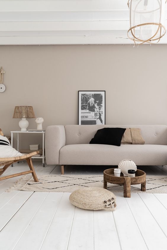an ethereal greige living room with a matching sofa, a rattan chair, a round carved coffee table and a side table on casters is amazing