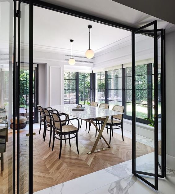 black frame and glass folding doors look very lightweight and separate the spaces subtly letting people enjoy light and views through these doors