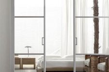 ethereal and light white white metal frame and glass pocket doors separate the bedroom from the living room in a chic way