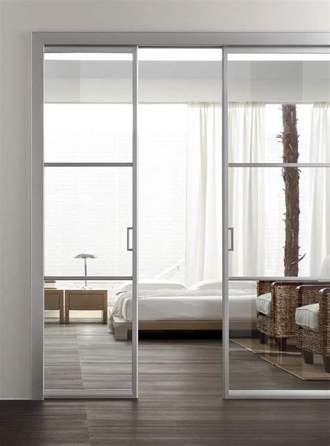 ethereal and light white white metal frame and glass pocket doors separate the bedroom from the living room in a chic way