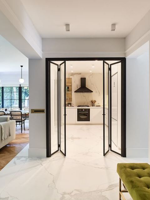 glass and black frame folding doors are a great idea to separate the kitchen that has no windows from the rest of the house and bring light inside