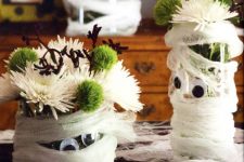mummy-styled planters with white and green blooms are adorable as Halloween centerpieces or just decorations