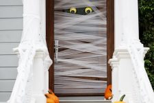 such a mummy-style front door is very easy to make, add a couple of pumpkins and fall leaves on the steps and voila – you have a Halloween porch