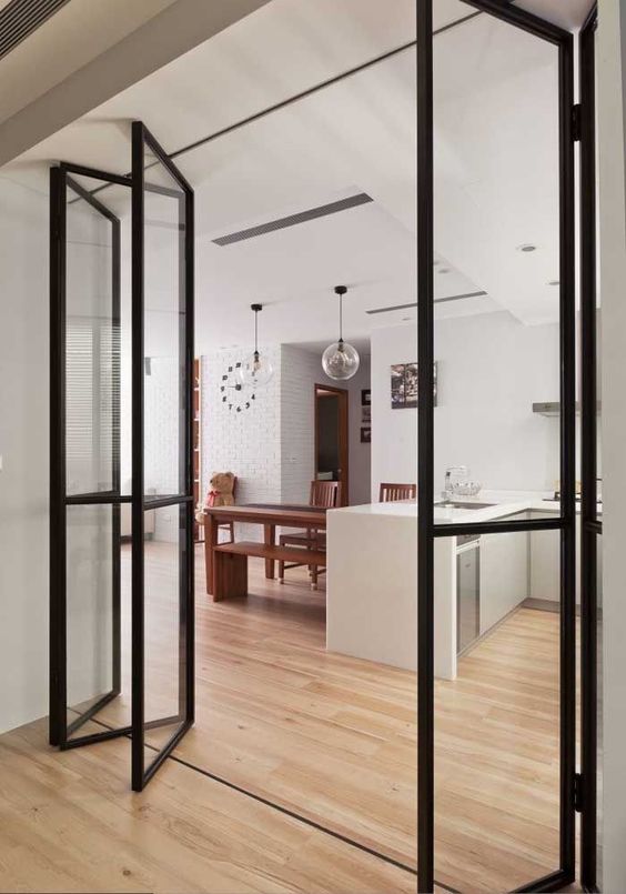 thin black frame and glass folding doors subtly separate the spaces and let the second nook without windows feel lighter than it is