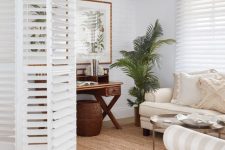 white shutter folding doors perfectly match the decor and delicately separate this small living room and the rest of the house