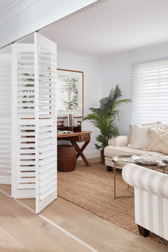 white shutter folding doors perfectly match the decor and delicately separate this small living room and the rest of the house