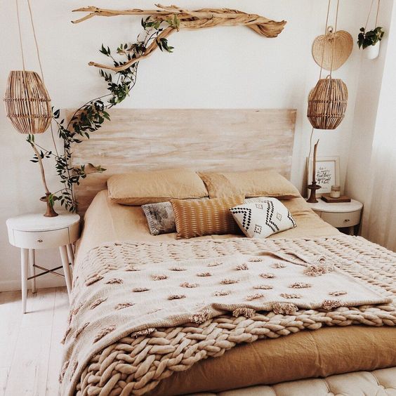 a natural bedroom with a stained bed, round white nightstands, a branch with greenery, woven lamps and cool mustard bedding