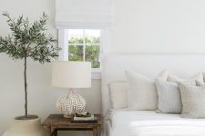 07 a beautiful all-neutral bedroom with a white upholstered bed, a wooden nightstand and a shabby chic bench, a potted plant and all neutral textiles