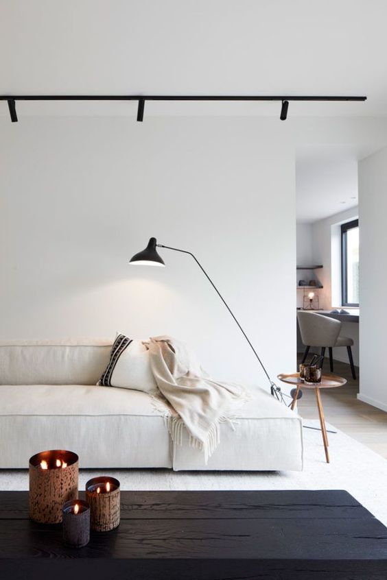 a minimalist living room in white, with dramatic black touches that contrast the rest of the space and make it wow