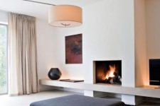 21 a minimalist living room with black furniture and a rug, a fireplace, an artwork, a lamp and neutral curtains