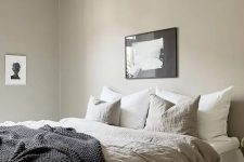 25 a greige bedroom with a large bed, lightweight nightstands, a beautiful pendant lamp and some lovely black and white artworks