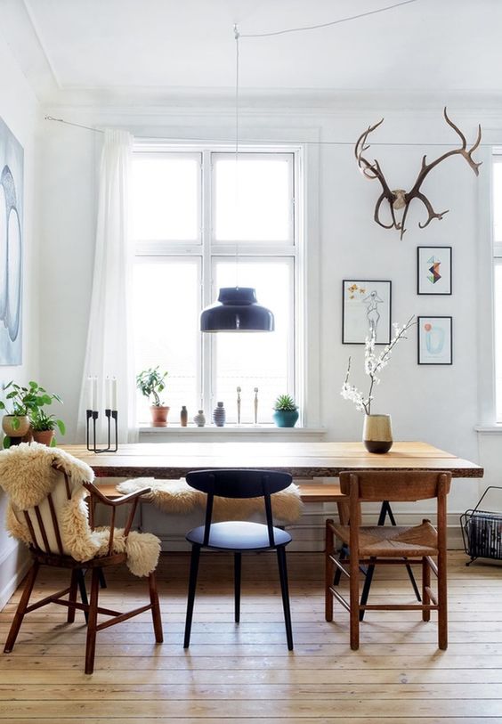 a Scandi dining space with a light-stained floor, a rich-stained table and chairs, black chairs and some potted plants is amazing