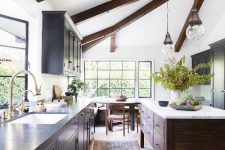 a chic modern farmhouse kitchen with a light-stained floor, dark wooden beams and a kitchen island that dominate over the space