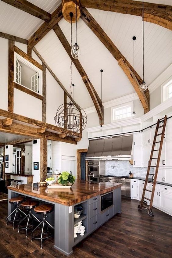 a farmhouse kitchen with white cabinetry, a grey kitchen island, a dark stained floor, rich-stained wooden beams and countertops
