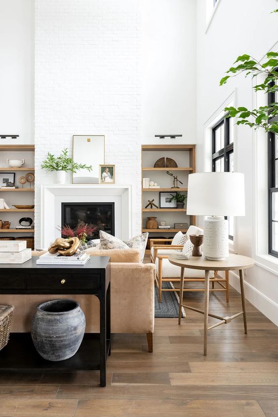 a light-filled living room with built-in shelves, a fireplace, comfortable modern furniture, a catchy laminate floor with several tones and light-stained furniture legs