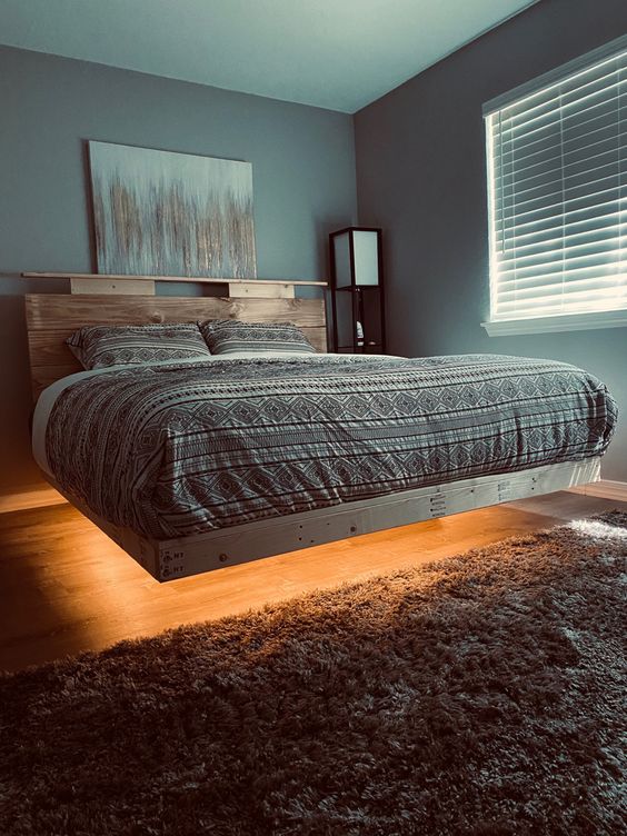 a lit up floating bed with printed bedding and a wooden headboard is a stylish idea for a modern bedroom and this light will create an ambience