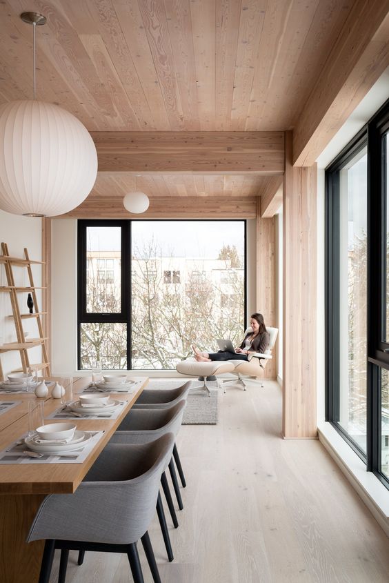 a luxurious minimalist dining room with much natural light, a whitewashed floor and warm and light tones of wood all over the space