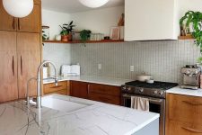 a mid-century modern kitchen with rich-stained cabinets and a white hood, a blue kitchen island and a light-stained floor