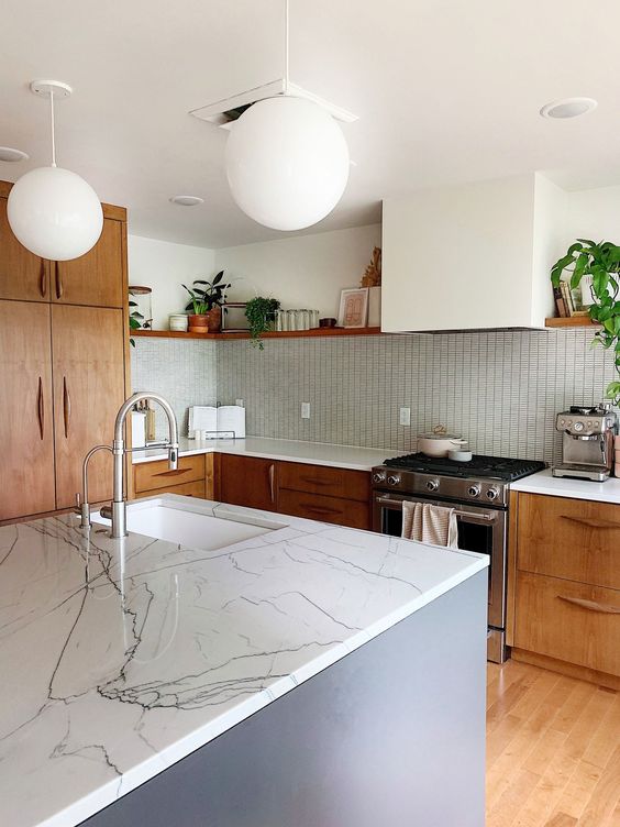 a mid-century modern kitchen with rich-stained cabinets and a white hood, a blue kitchen island and a light-stained floor
