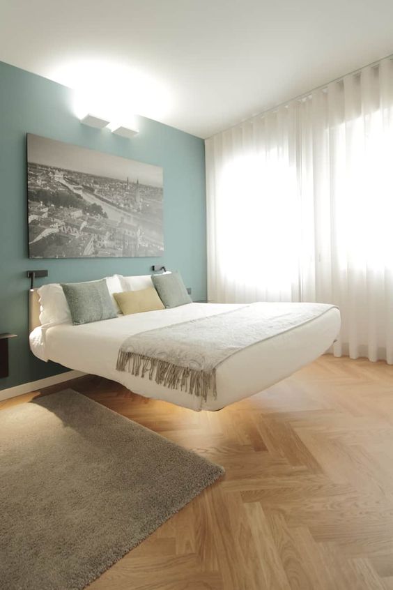 a neutral bedroom with a baby blue accent wall, a white floating bed with lights, a fluffy rug and some pillows is cool