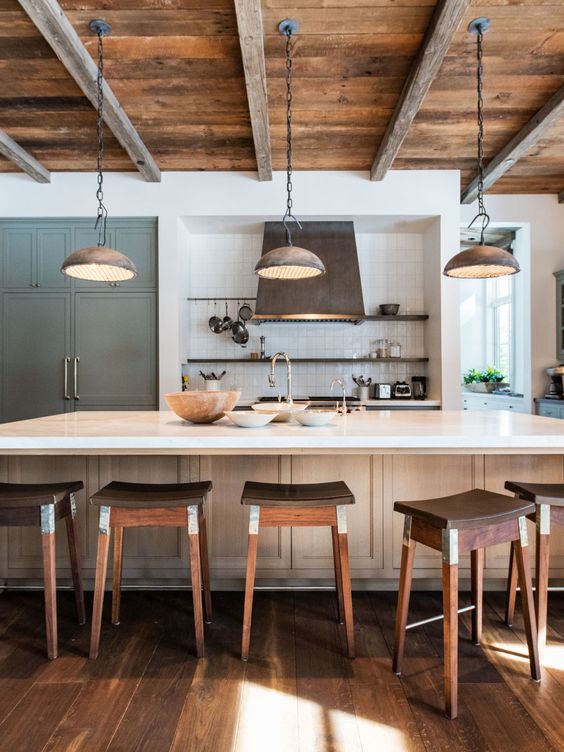 a rustic kitchen with light stained cabinetry, open shelving, built in storage furniture, rich stained stools and a reclaimed wood ceiling