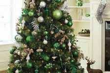 06 a beautiful forest glam Christmas tree with lots of green and white ornaments of various sizes, silver leaves, lights and branches plus a white star on top