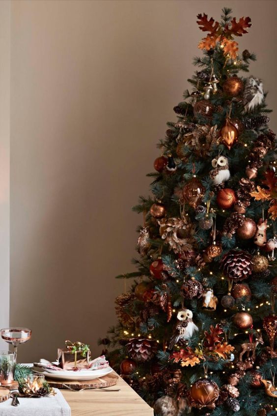 a bold woodland glam Christmas tree with copper and brown ornaments, sequin pinecones, lights, leaves and owls hanging