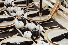 10 a lovely and refined Thanksgiving tablescape with a striped runner and black napkins, black and white pumpkins, tall and thin black candles and gold cutlery