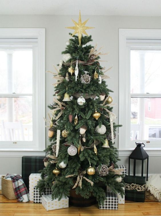 a woodland glam Christmas tree with white and gold ornaments, acorn, star, icicle and vine ornaments and a large gold star on top the tree