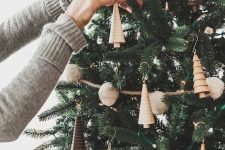 14 a woodland Christmas tree with pompom garlands, lights, wooden tree-shaped ornaments and burlap ribbons is a creative and cool idea