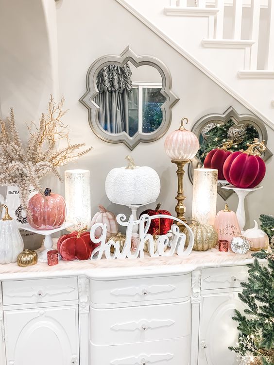 a lovely glam Thanksgiving console table with fuchsia, blush, white and gold pumpkins, calligraphy, candles and blooming branches is wow